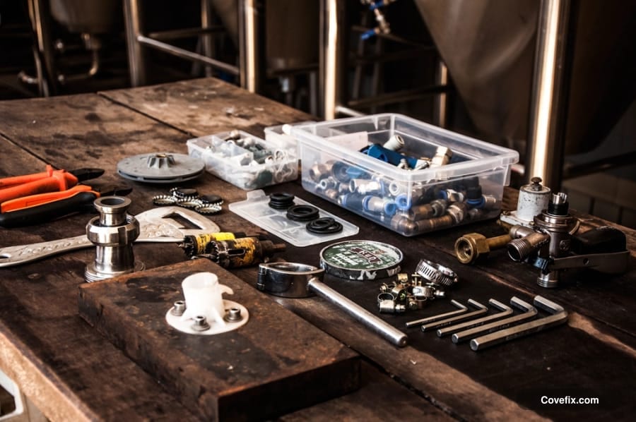 Toilet tank repair parts, gaskets, seals, and fittings laid out on a workbench